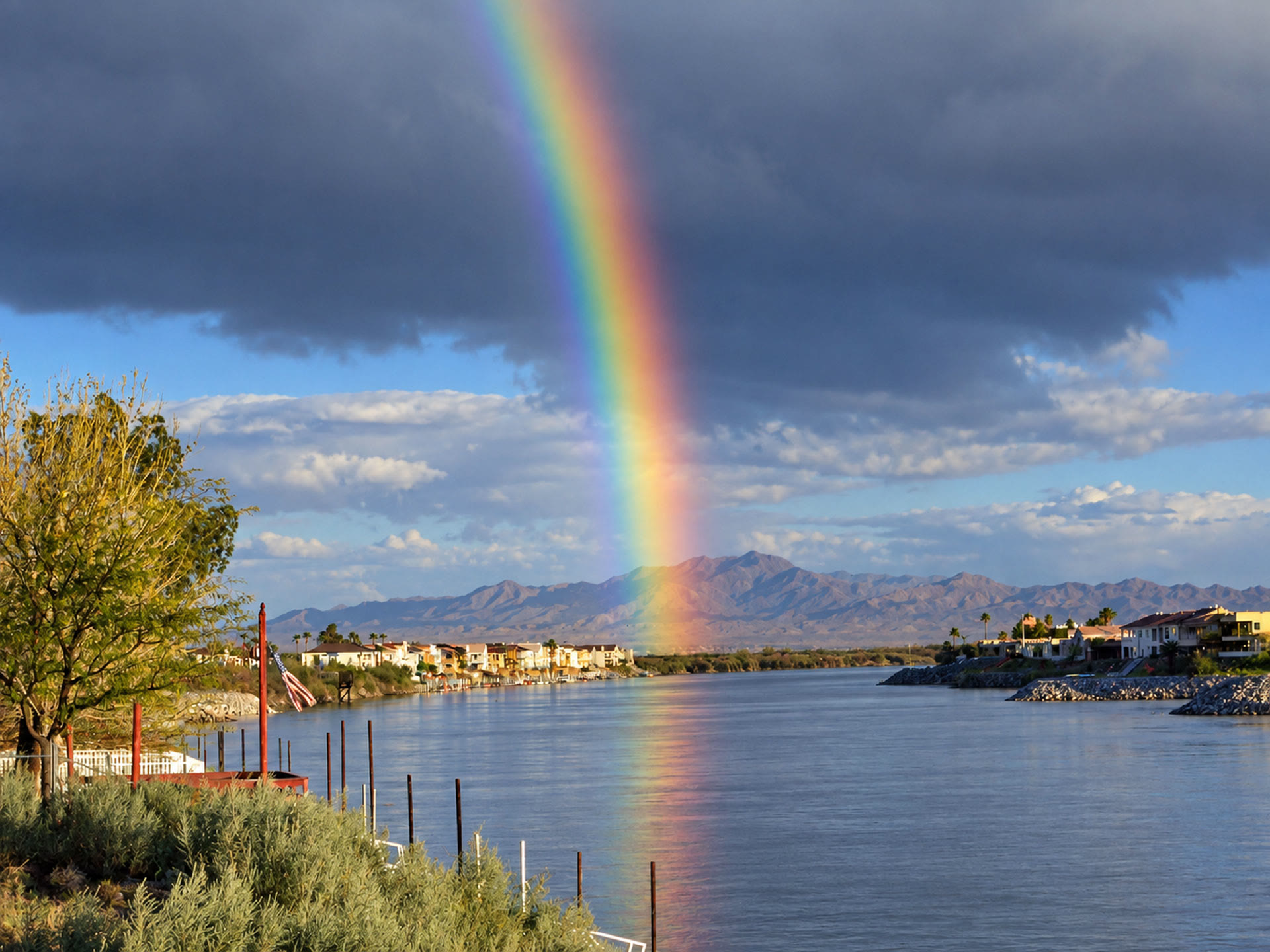 River Life on the Colorado River: Rainbow Views Bright rainbow reflecting on the Colorado River, with waterfront homes, desert mountains and storm clouds in the background.